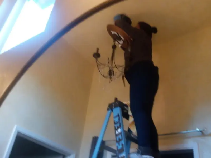 Electrician installing a chandelier in a Piedmont residence